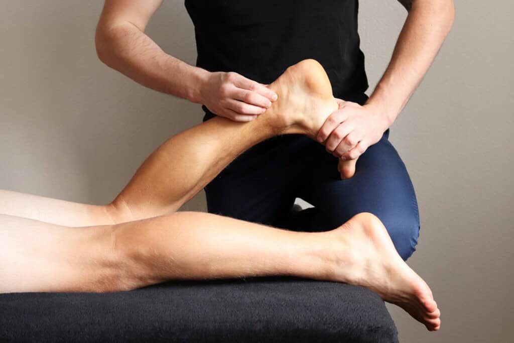 Massage of myofascial trigger points on ankle of male client to release tension caused from tendonitis.
