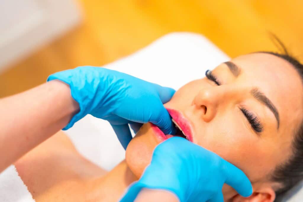 Woman receiving an intraoral jaw massage for to treat TMJ disorder.