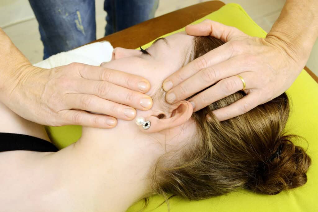 Woman receiving external jaw massage to treat TMJ disorder.