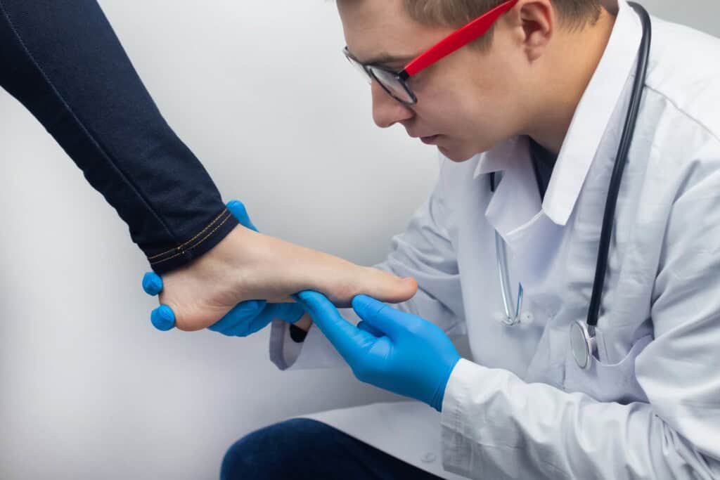 A doctor examines a woman's foot to determine the cause of her pain.