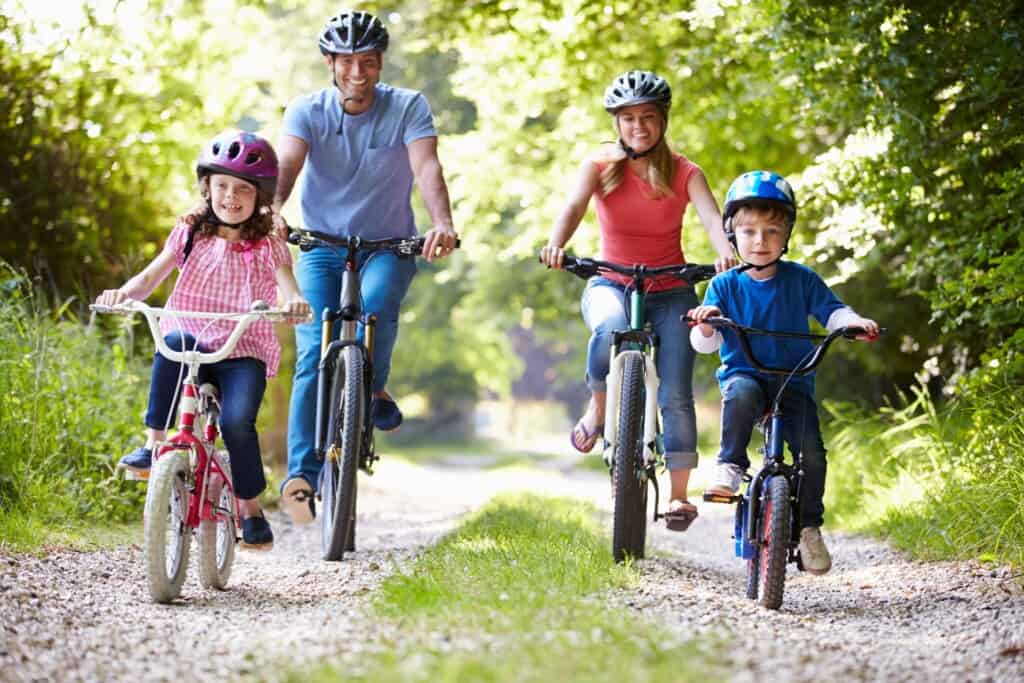 A family, mother, father, son, and daughter on a bike ride together on a beautiful trail.