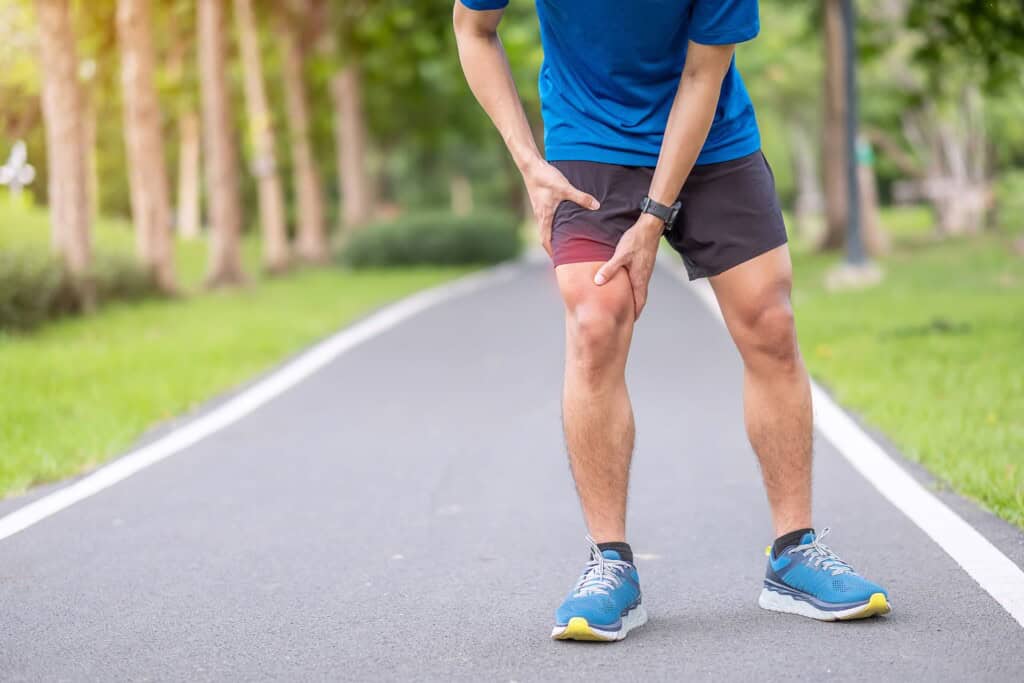 Young adult male with muscle pain during running due to Iliotibial Band Syndrome.