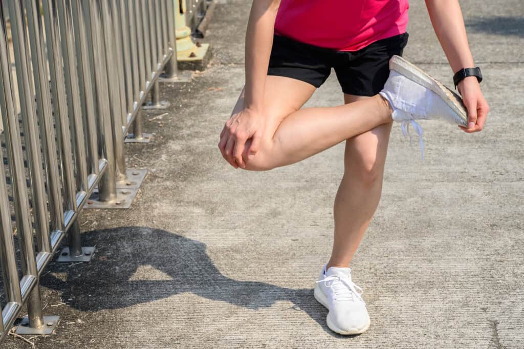 Cropped shot of runner woman do stretching to relieve tight IT Bands.