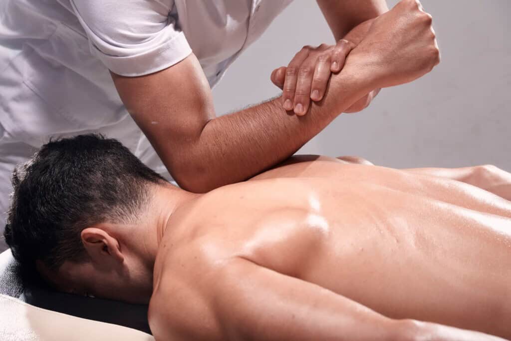 Bodyworker using his elbow to apply firm pressure to the back of a client's neck to address forward head posture.