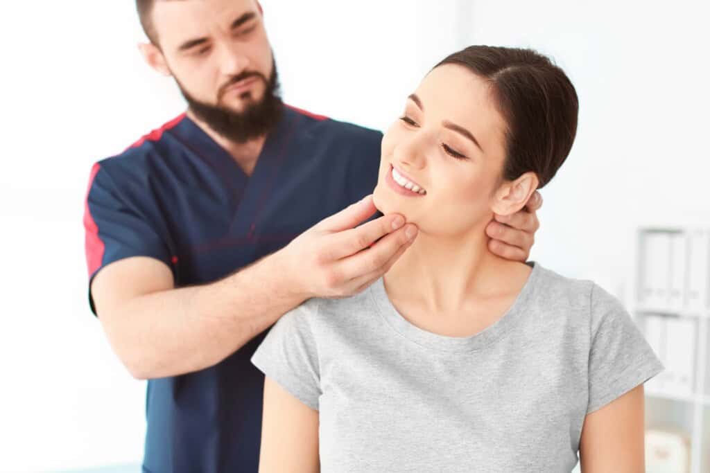 Bodyworker assessing a clien'ts neck mobility by gently tilting her head to the side.