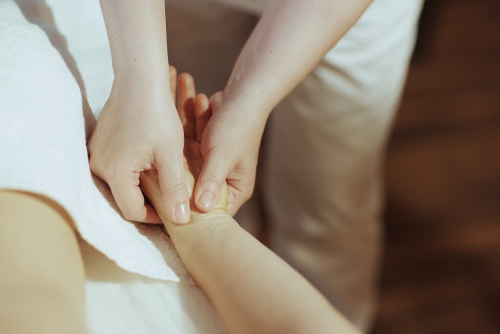 Closeup of a bodyworker's hand gently massaging a client's sprained wrist to aid healing.