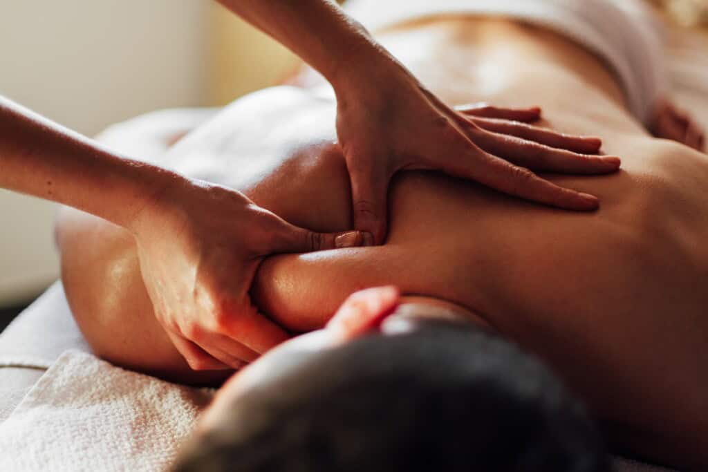 Bodyworker using skilled techniques to relieve tension in the upper back, applying focused pressure to the shoulder muscles.