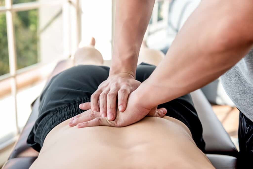 A person with lordosis receives bodywork therapy on a table near a window, with natural light enhancing the calming and restorative atmosphere.